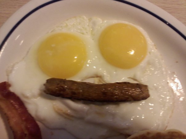 two fried eggs with sausage are in the shape of a face