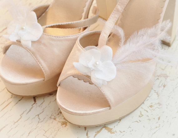 pair of high heels decorated with white flowers and a feather