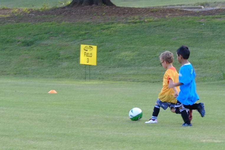 two boys play soccer in the park