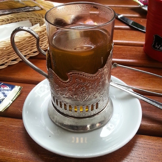 a cup of tea sits on a white saucer on a wooden table