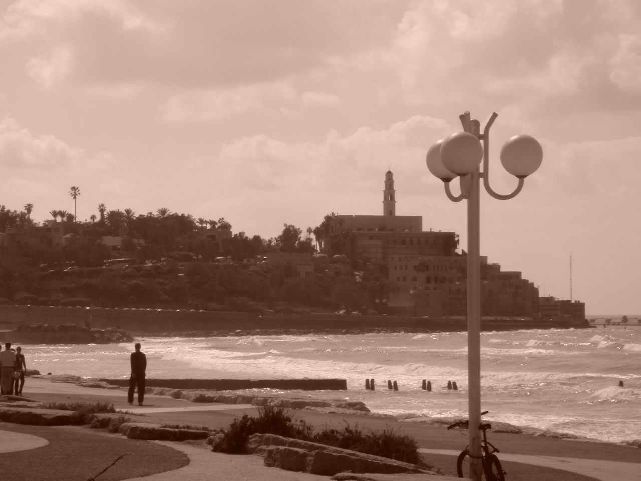 people are walking near the ocean and on the sand