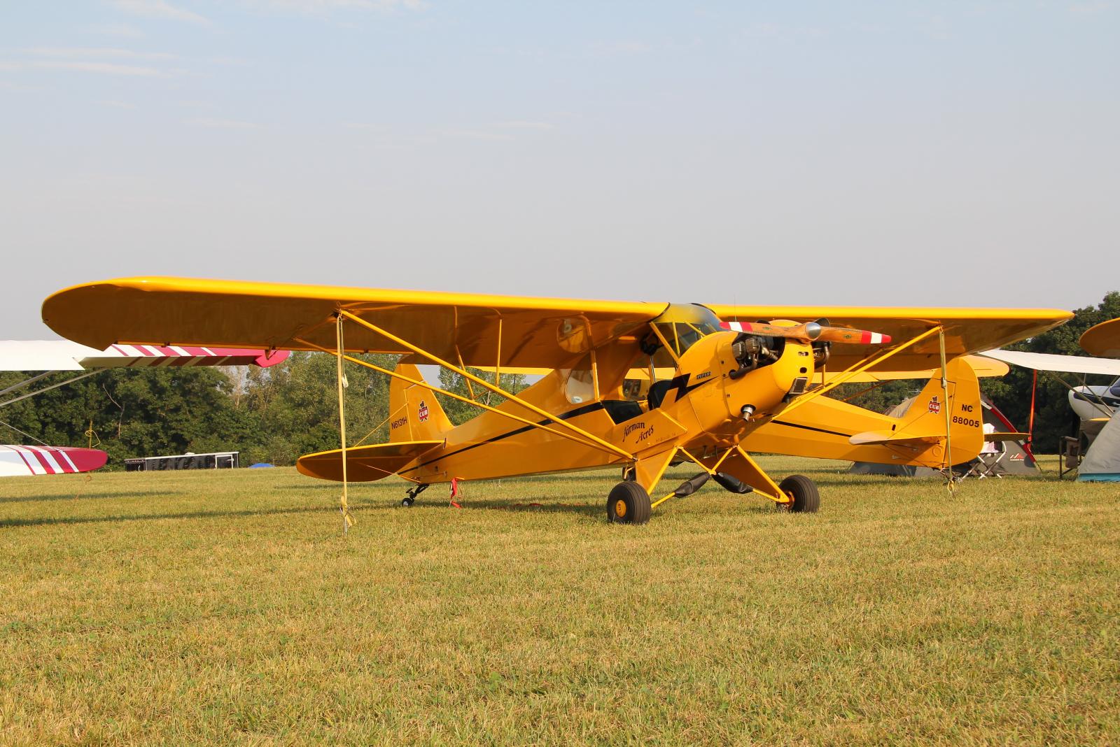 a small yellow plane parked on top of grass