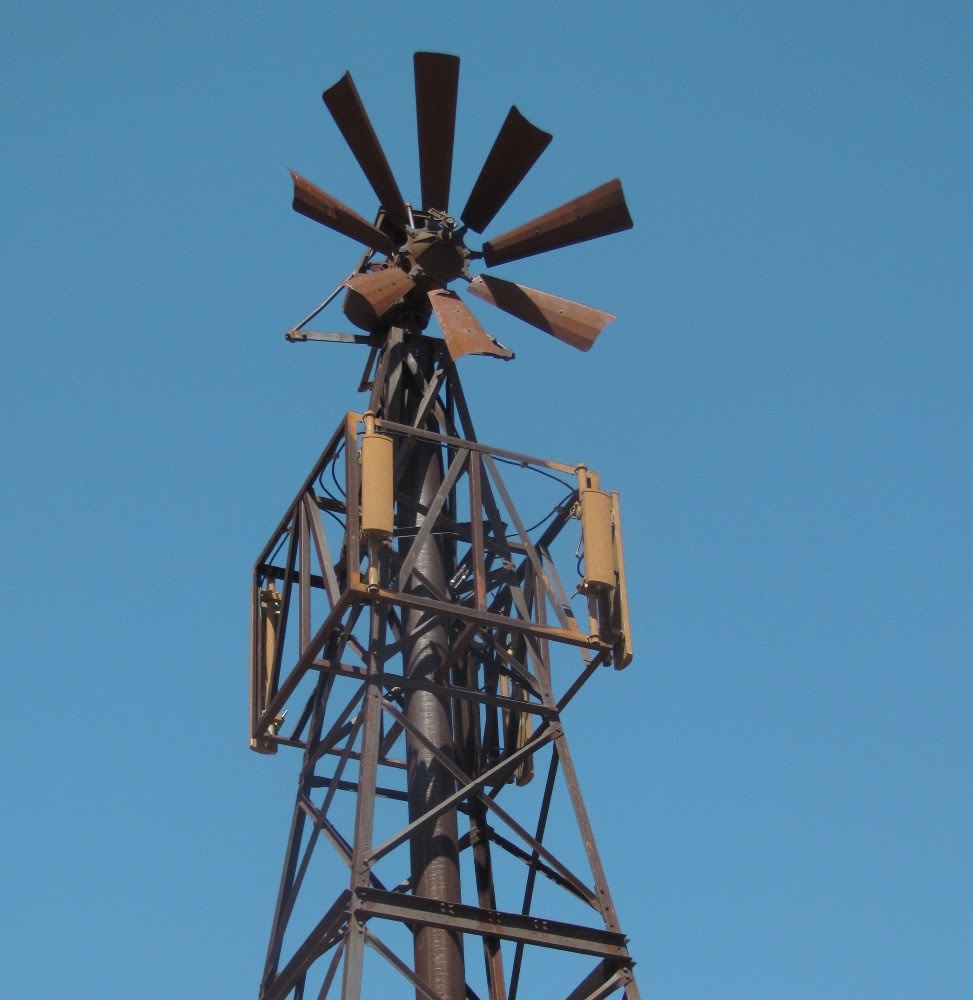 the top of an old metal tower with two windmills on it