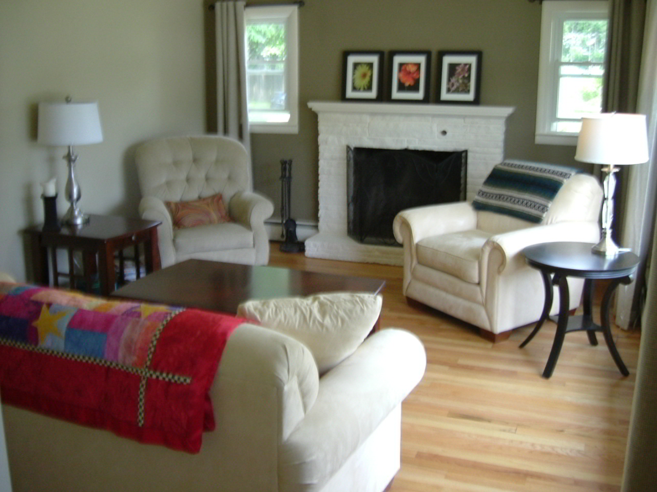 the room has a chair, couch, ottoman and fire place in it