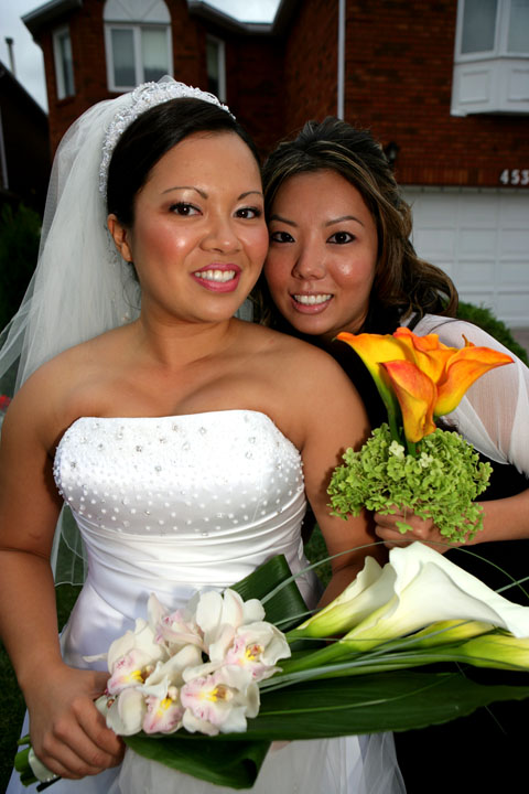 two people in white dress holding flowers and smiling for the camera