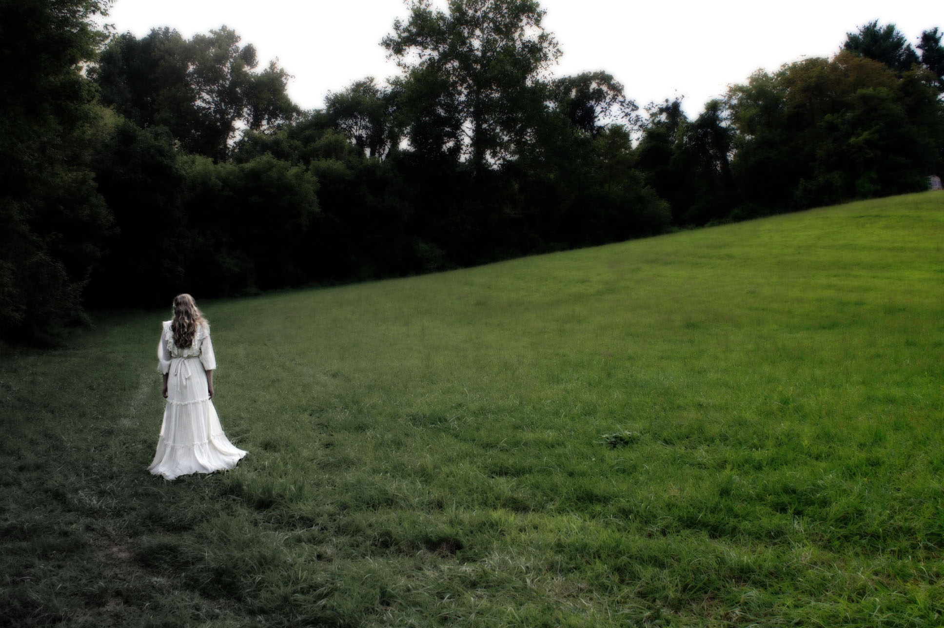 a woman in a white wedding dress walks through the grass