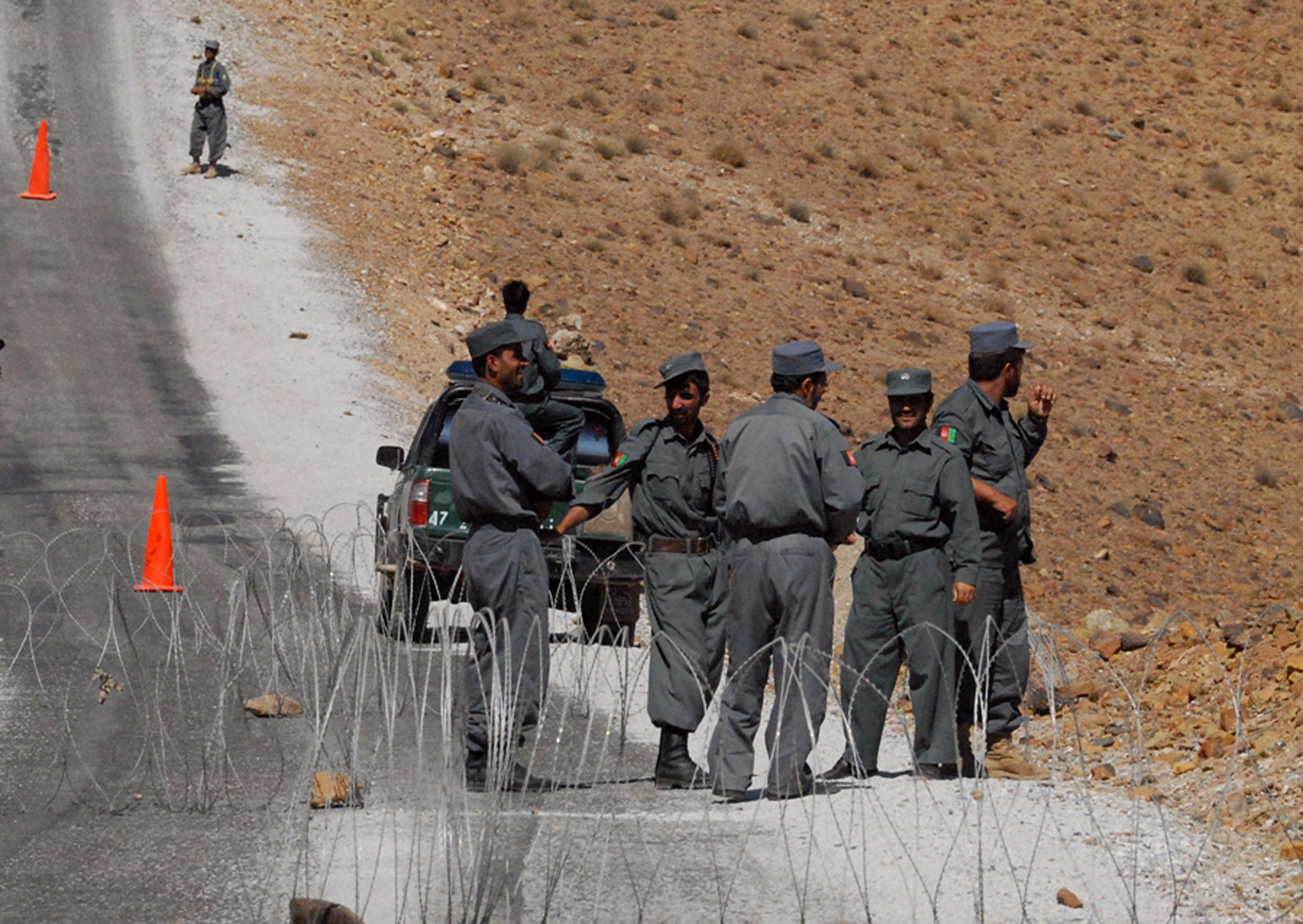 several policemen stand by a truck on the side of a road