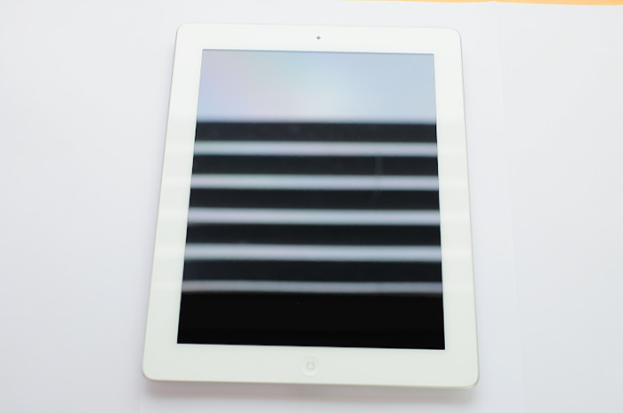 white electronic tablet with vertical blinds as background