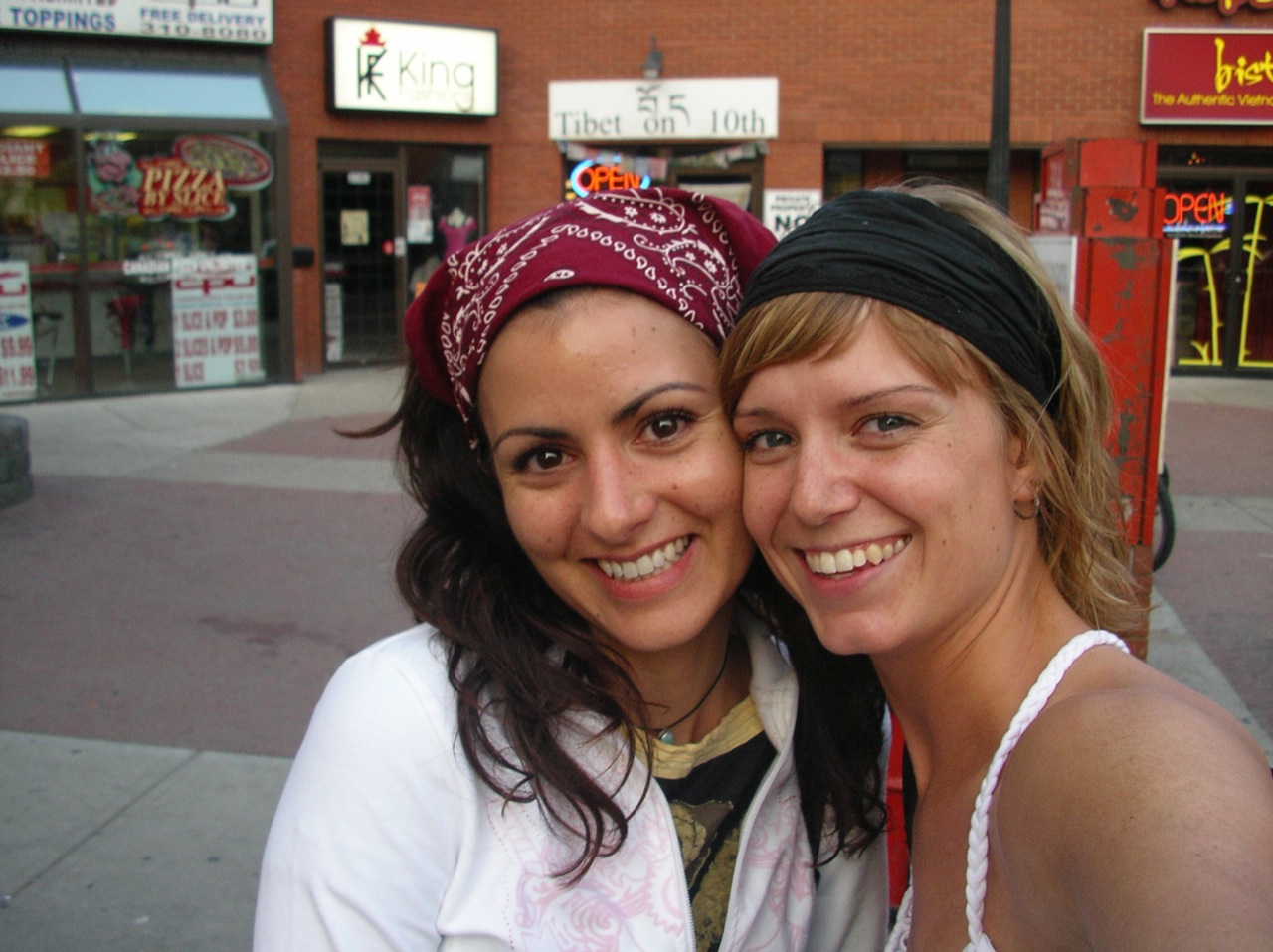 two young women posing for the camera on the street