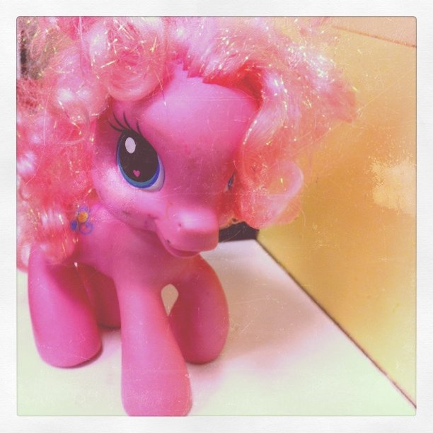 the pony doll is sitting on the ground with pink hair