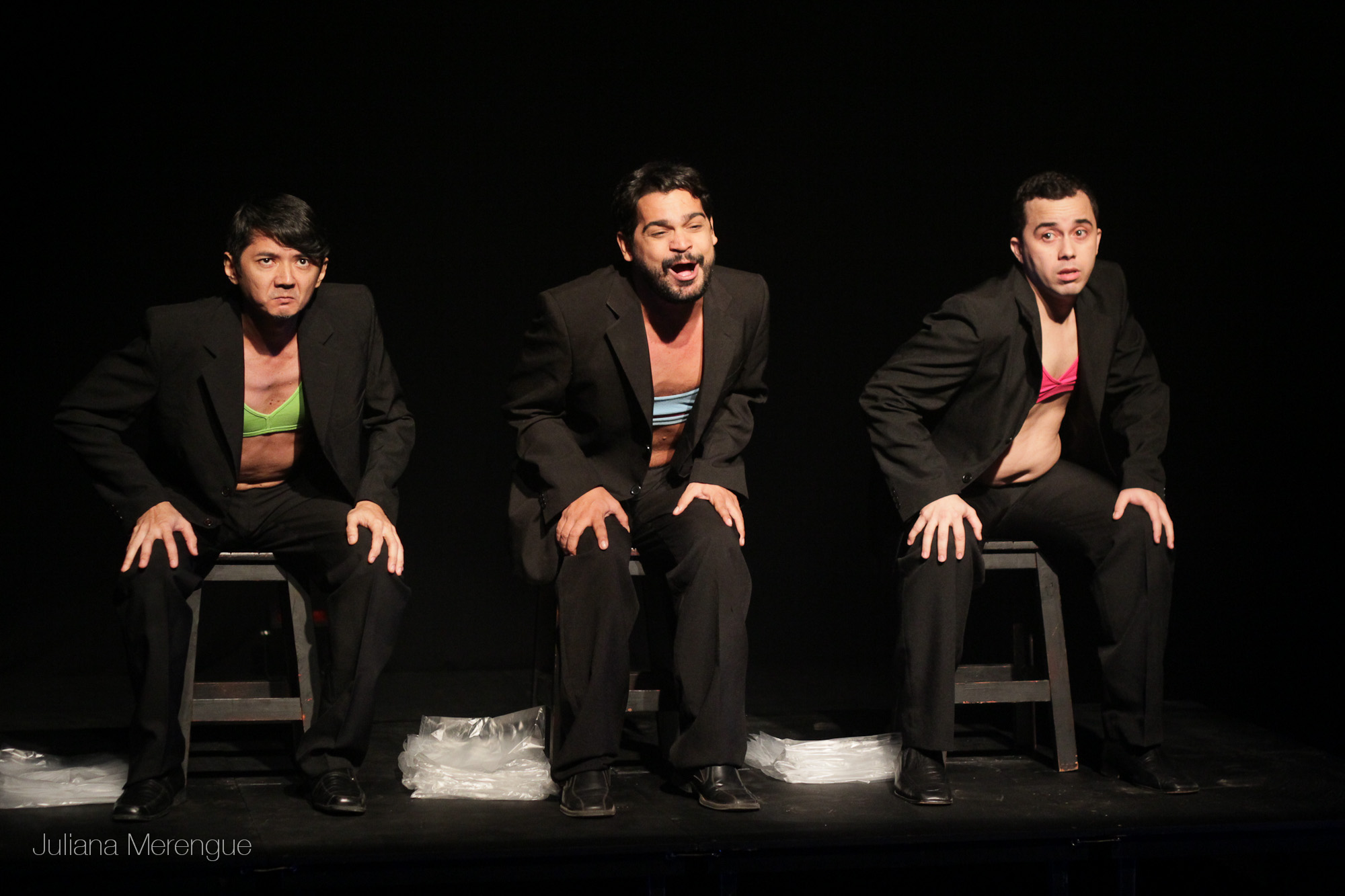 three men in suits on a chair in the dark