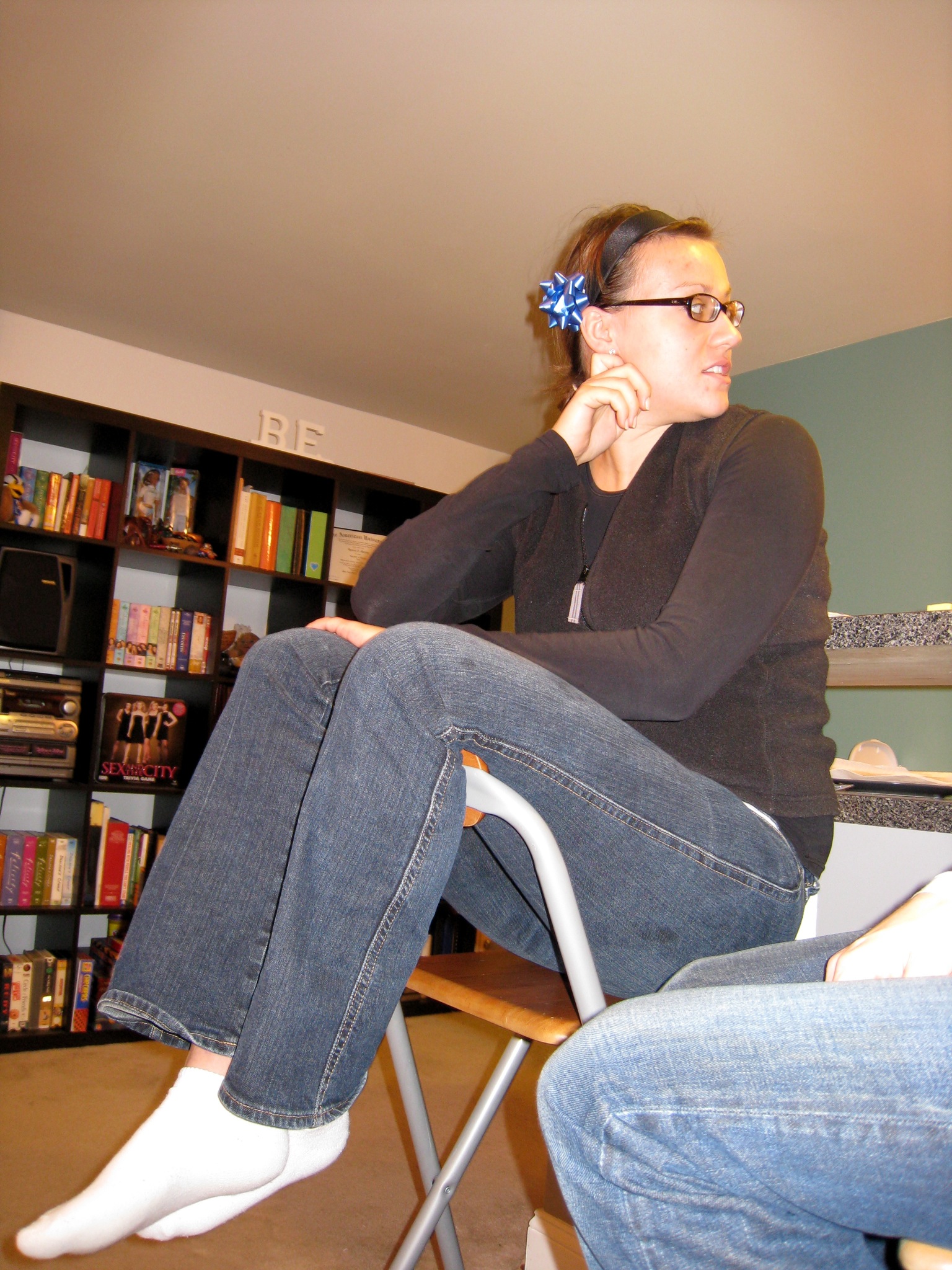 a woman wearing jeans and shoes, sitting on a stool