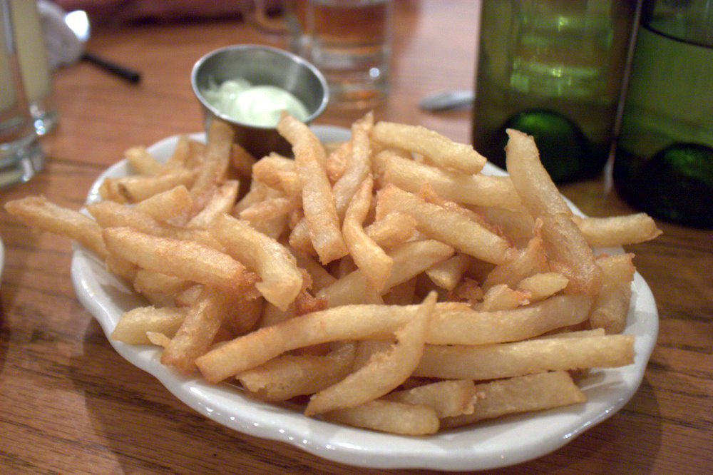 some fries sitting on a white plate on a table