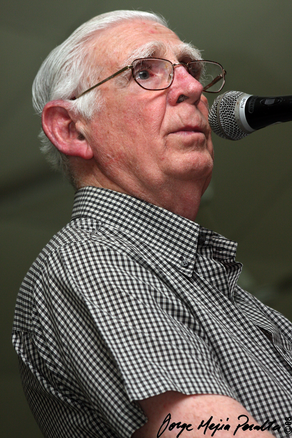 a man with white hair and glasses is singing into a microphone
