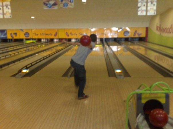 a man holding up two bowling balls in a bowling alley
