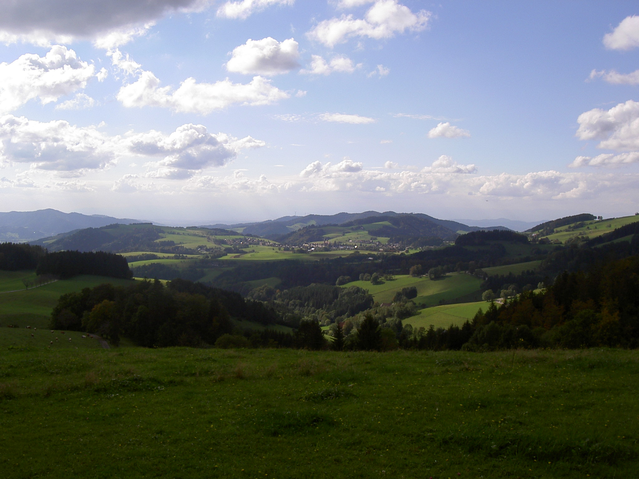 the view from the top of a mountain with green hills