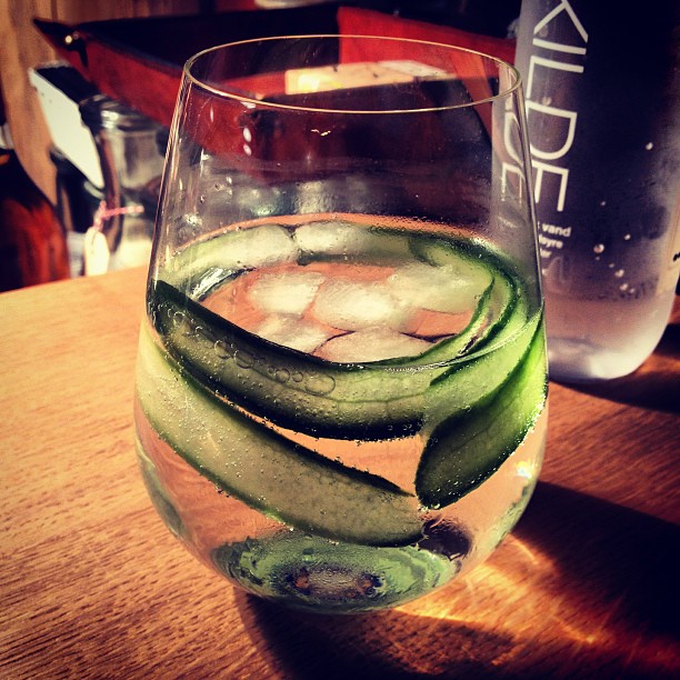 a clear wine glass with water and cucumbers