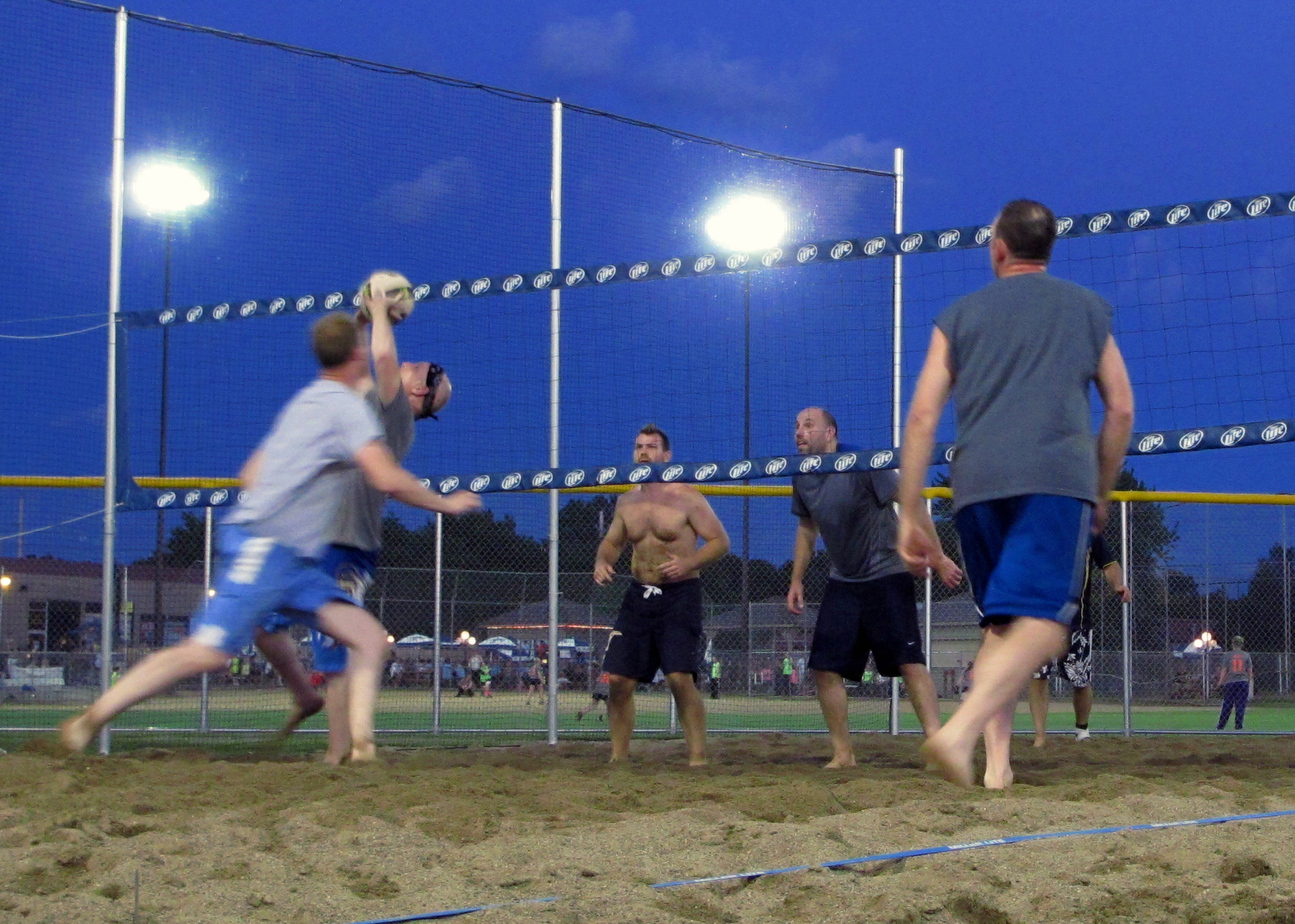 people in the sand are watching an at bat game