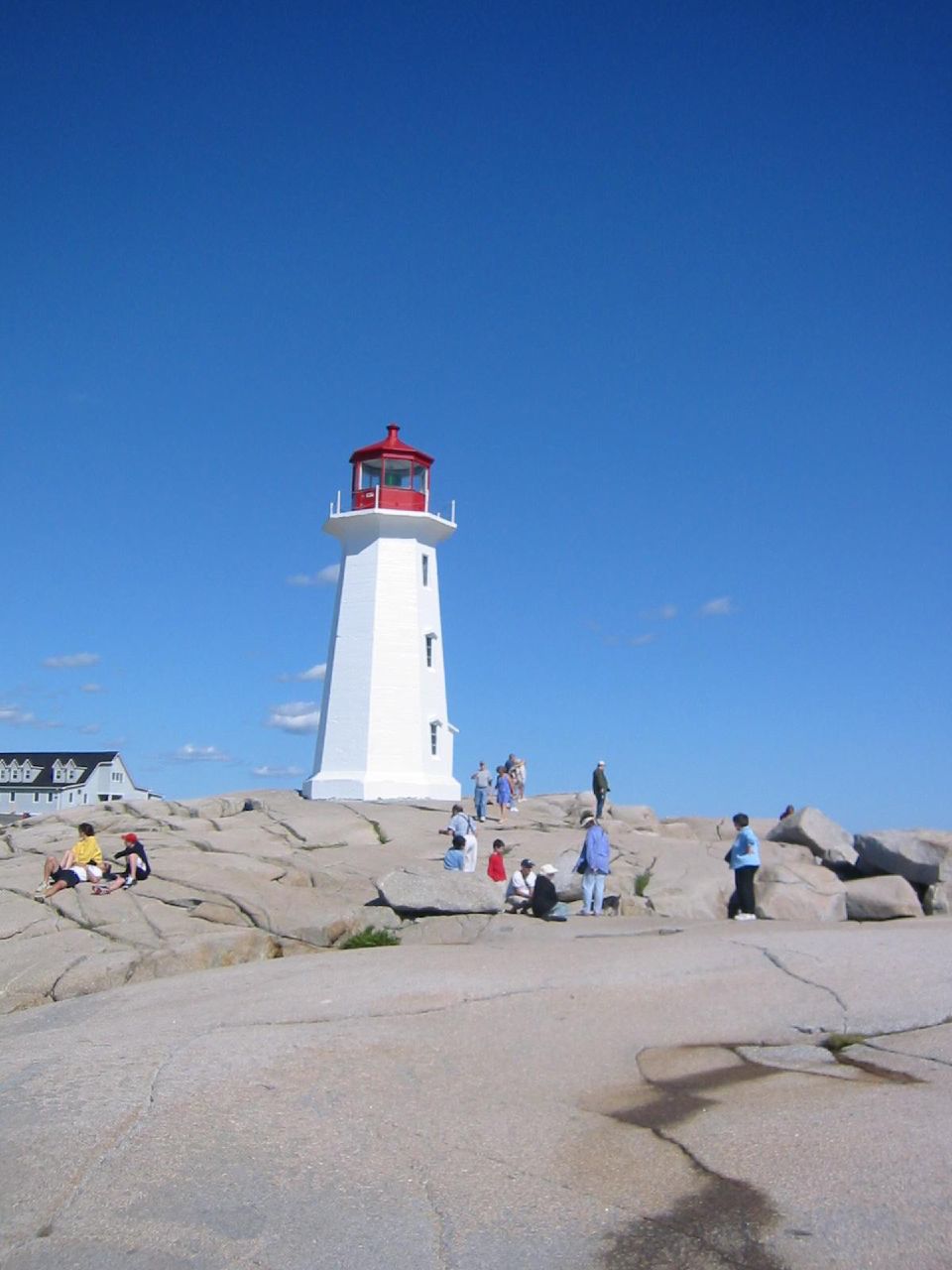 a lighthouse with people standing around it near rocks