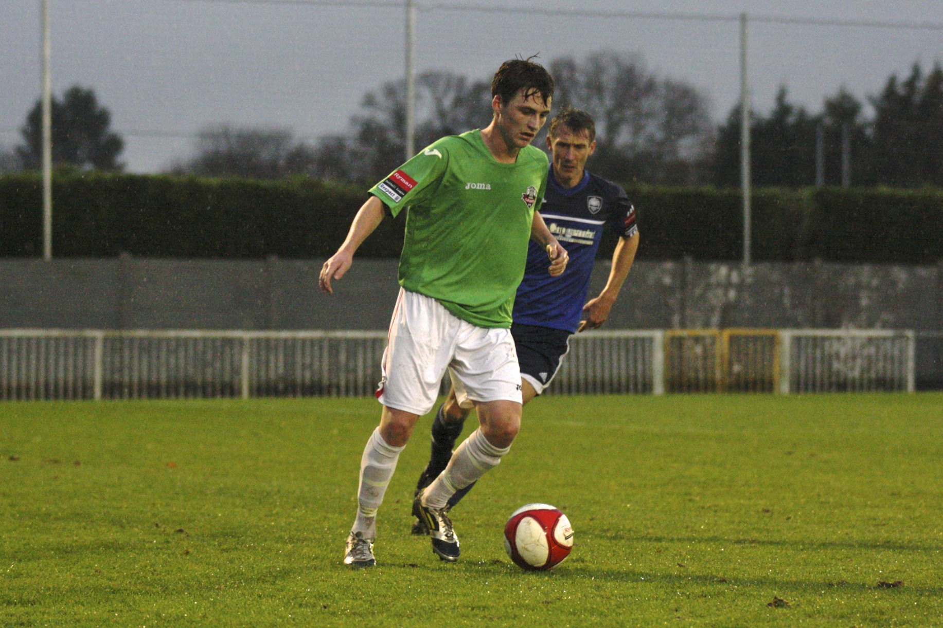 two men in green jerseys play soccer on a field