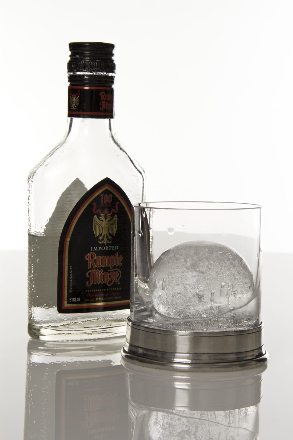 an ice ball next to a bottle and a glass
