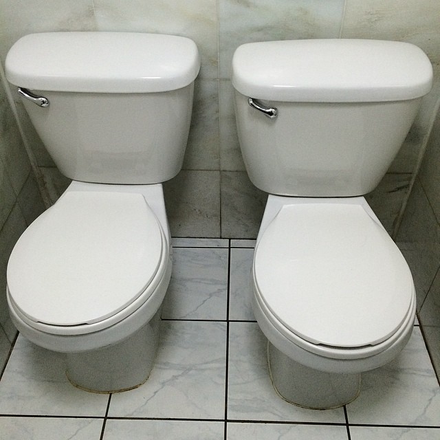 a pair of white toilets in a public restroom