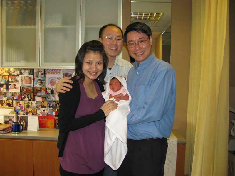 a man holding a baby with another man smiling next to him