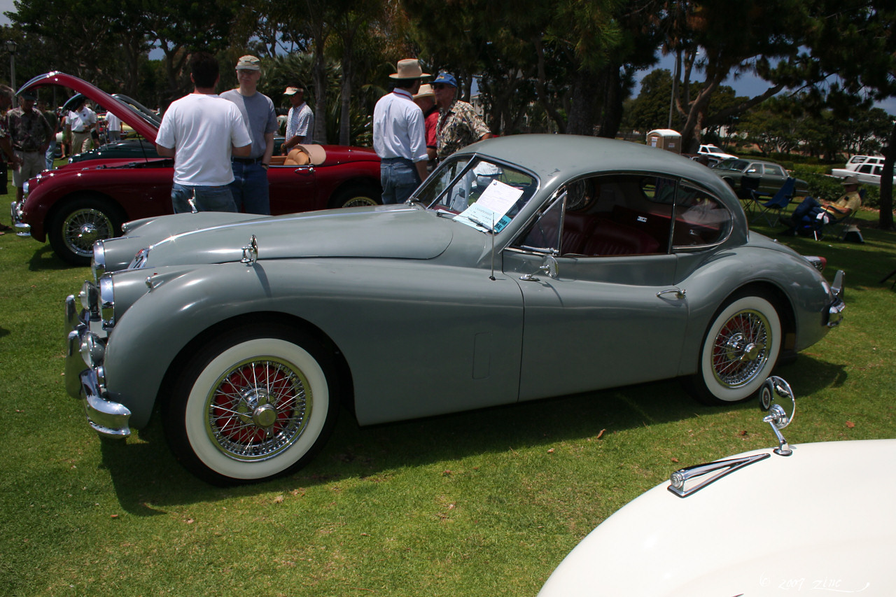 a vintage sports car parked in a grass covered field