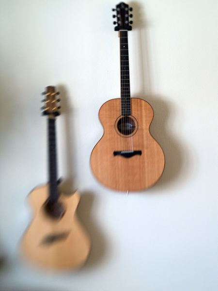 a wooden guitar hanging on a wall near another guitar
