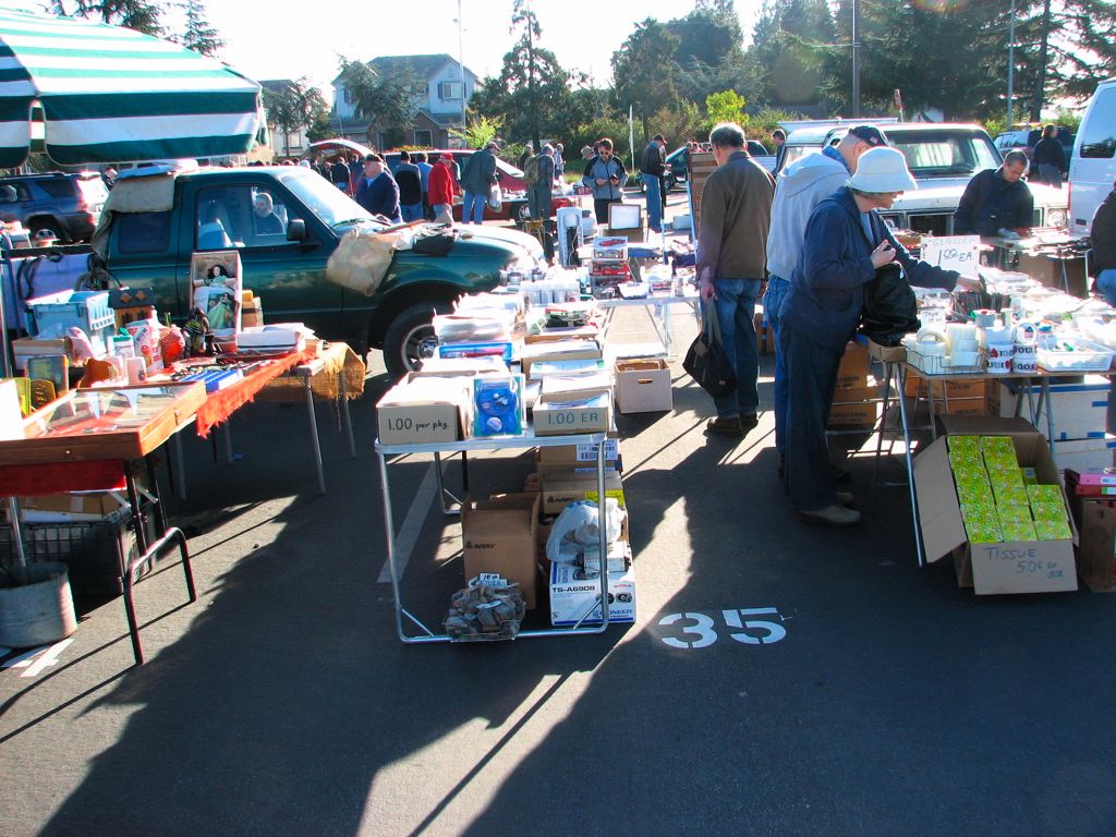 people shopping in a flea market with tables full of merchandise