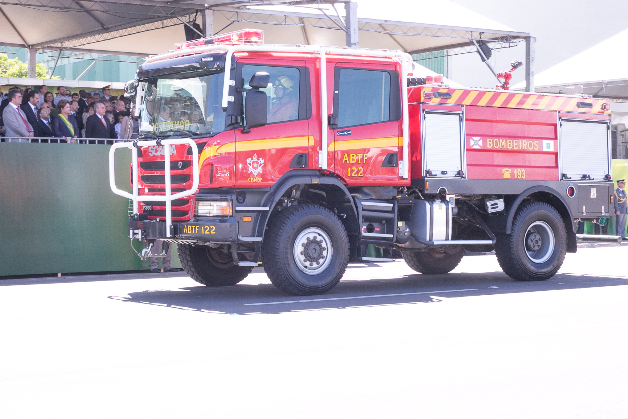 red and yellow utility truck in open area with spectators