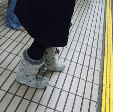 a pair of feet and leg warmers in snow boots on an indoor tile covered platform