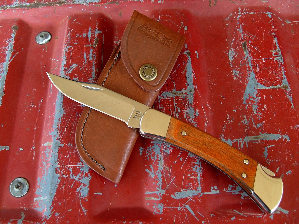 a knife with a tan sheath and brown leather case