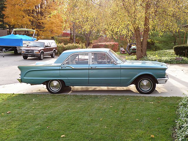 an old fashion car parked next to other cars on the grass