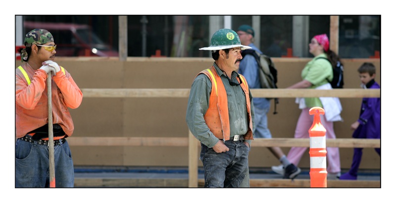 a man in safety clothing standing next to another man with a hard hat
