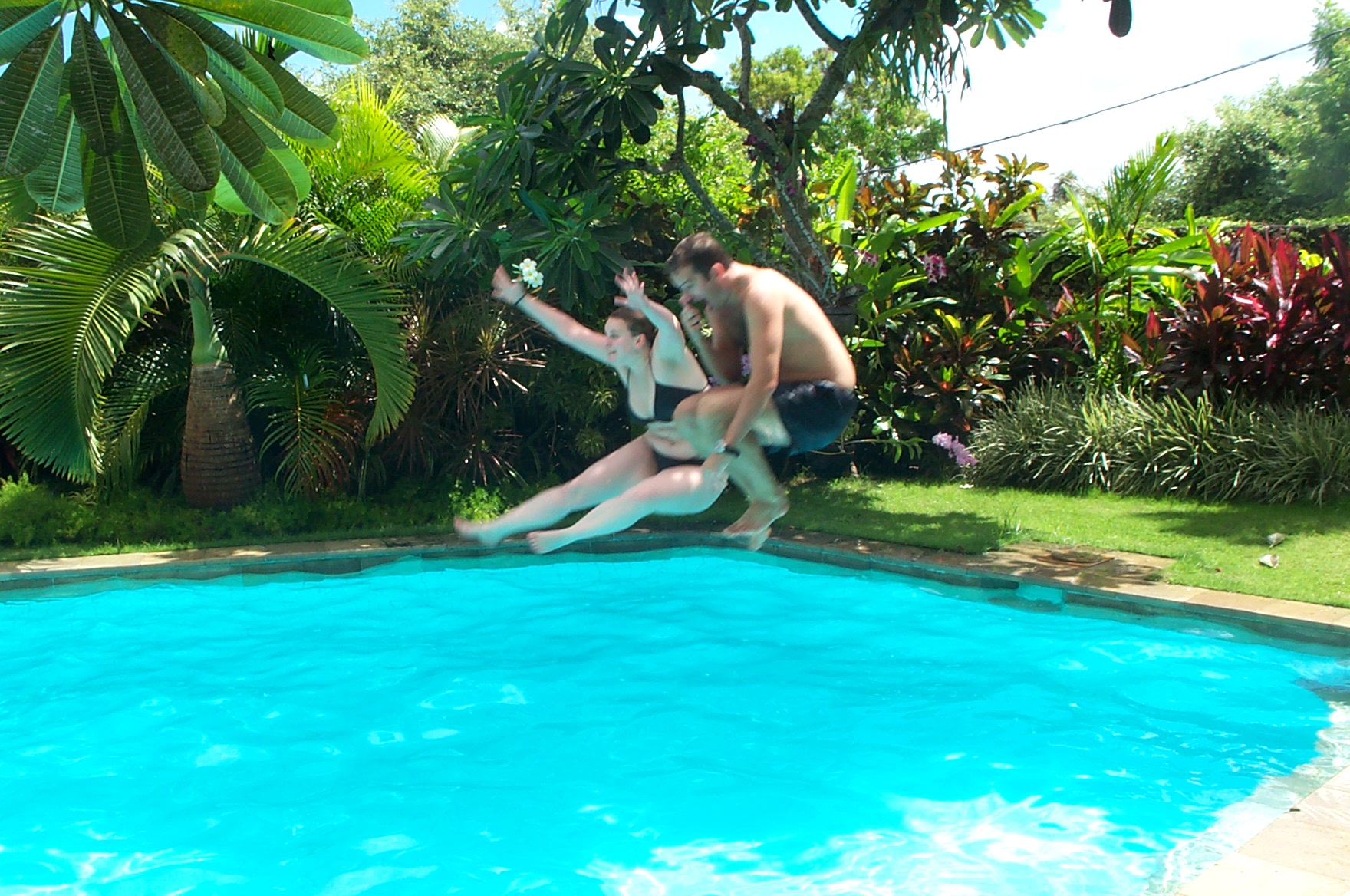 two men in swim suits jumping into a pool