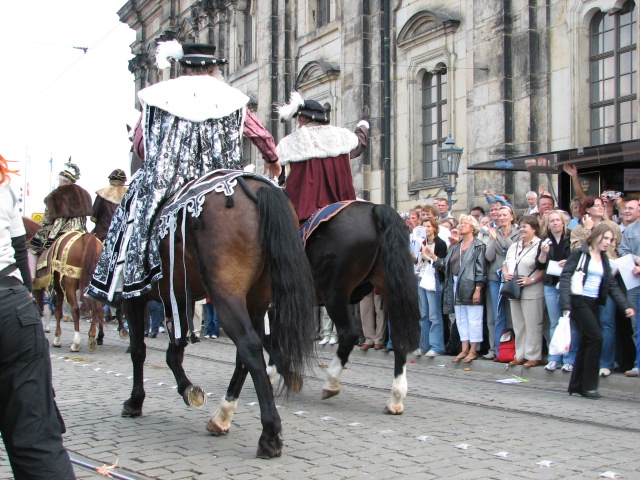 men dressed in costumes on horseback being lead down the street