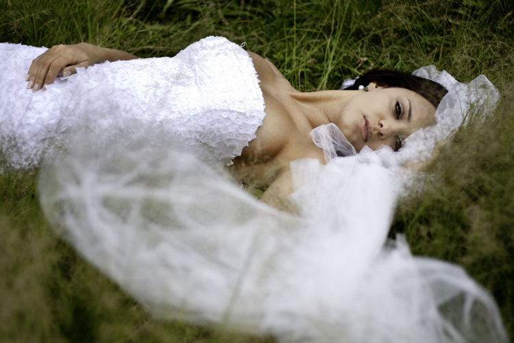 a woman wearing a white gown laying in a field