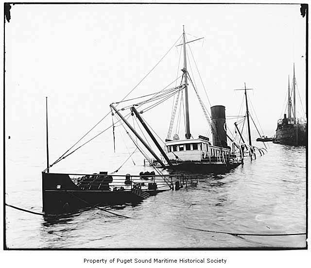 a tug boat with two boats in the background