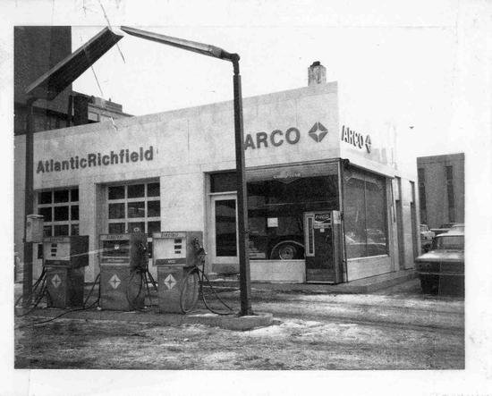an old gas station with two old time pump and cars in front