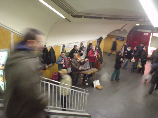 people standing in a subway station and a man is walking down stairs