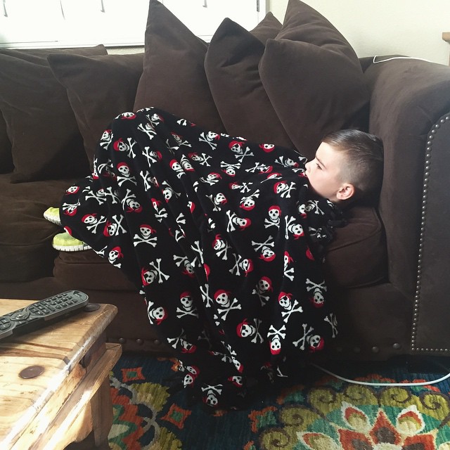 a boy that is sleeping under a blanket