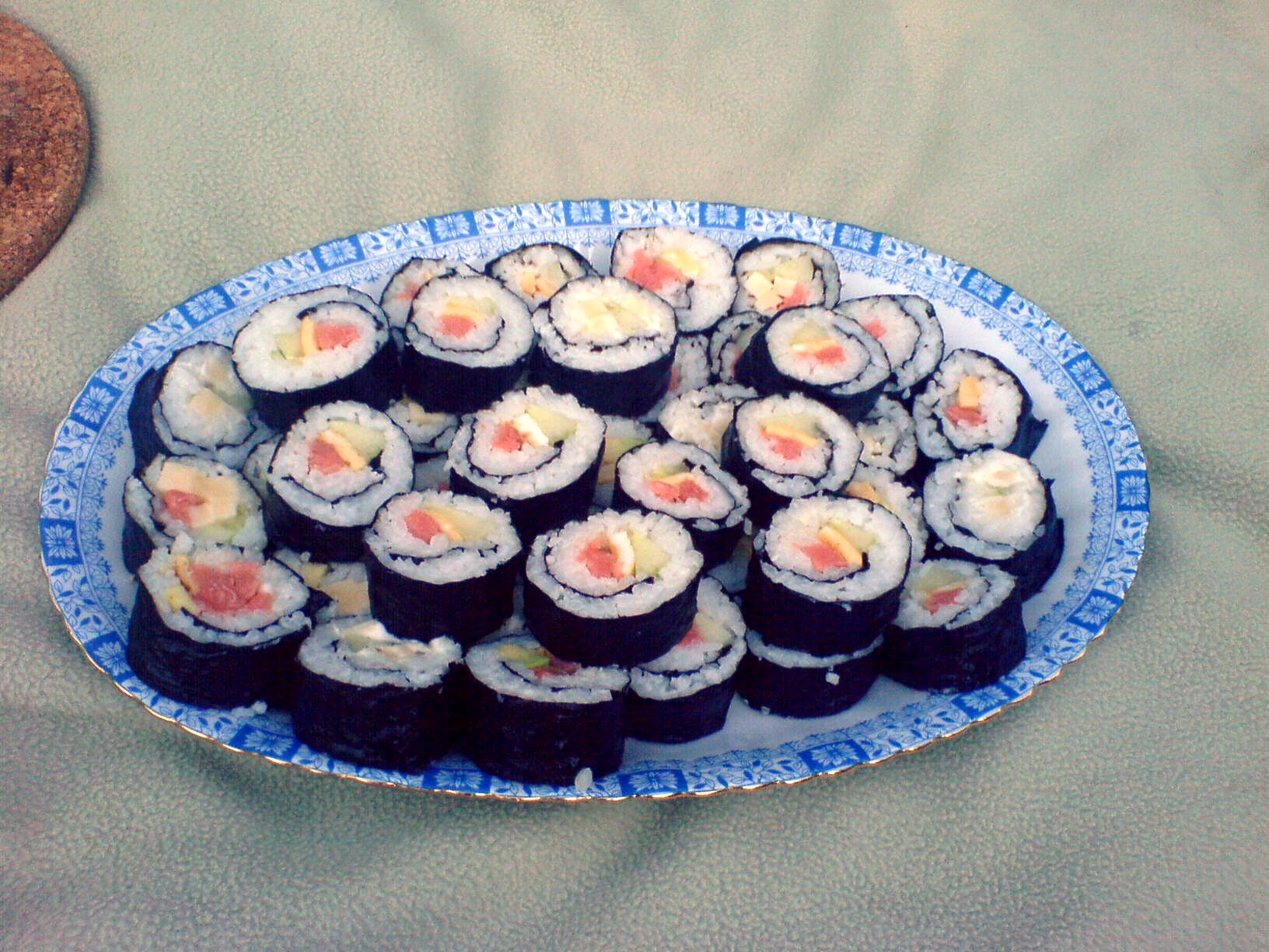 a plate full of black sushi on a green tablecloth