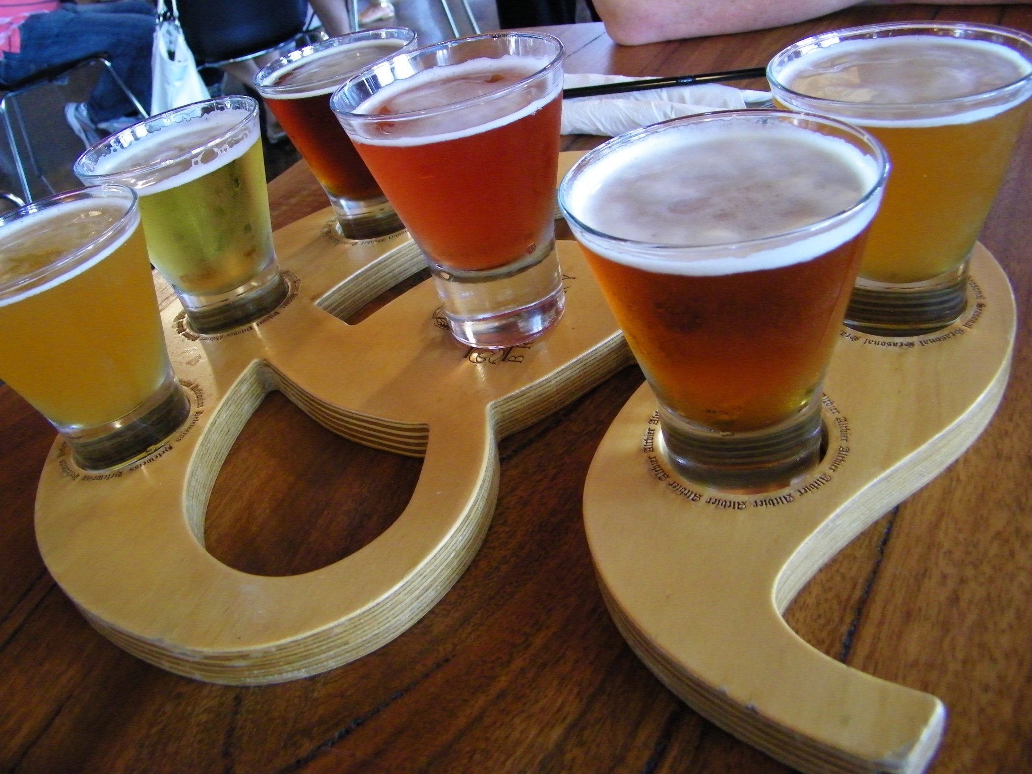 many different glasses of beer on top of a board