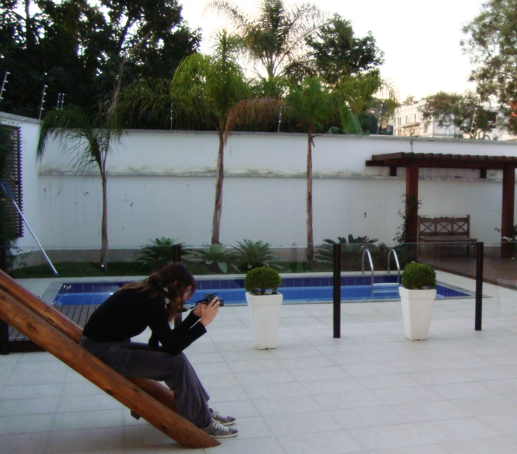 a woman taking a po on her phone near a pool