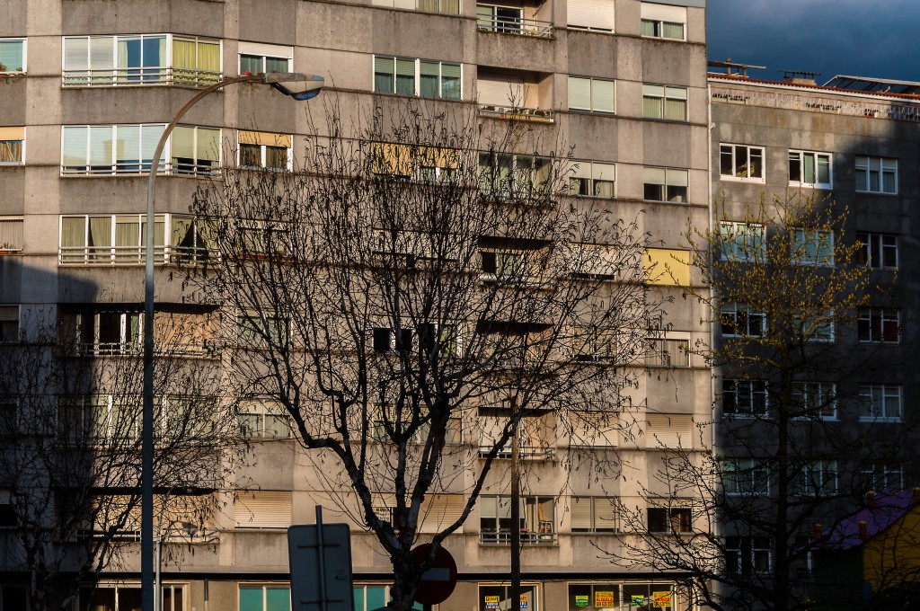 a large building that has many windows and lots of trees in front of it