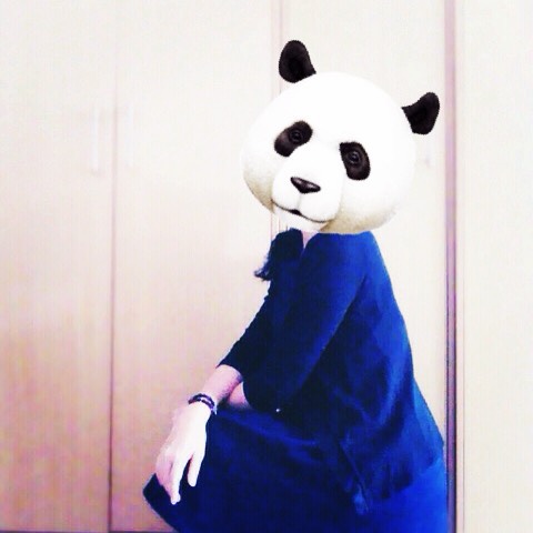 a woman in a panda suit sitting down with a panda mask on her head