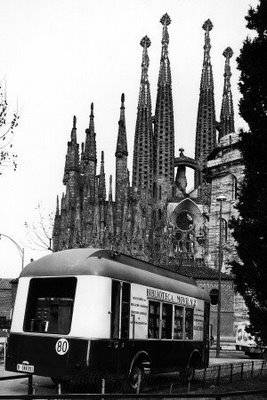 a small train rides past a very tall cathedral