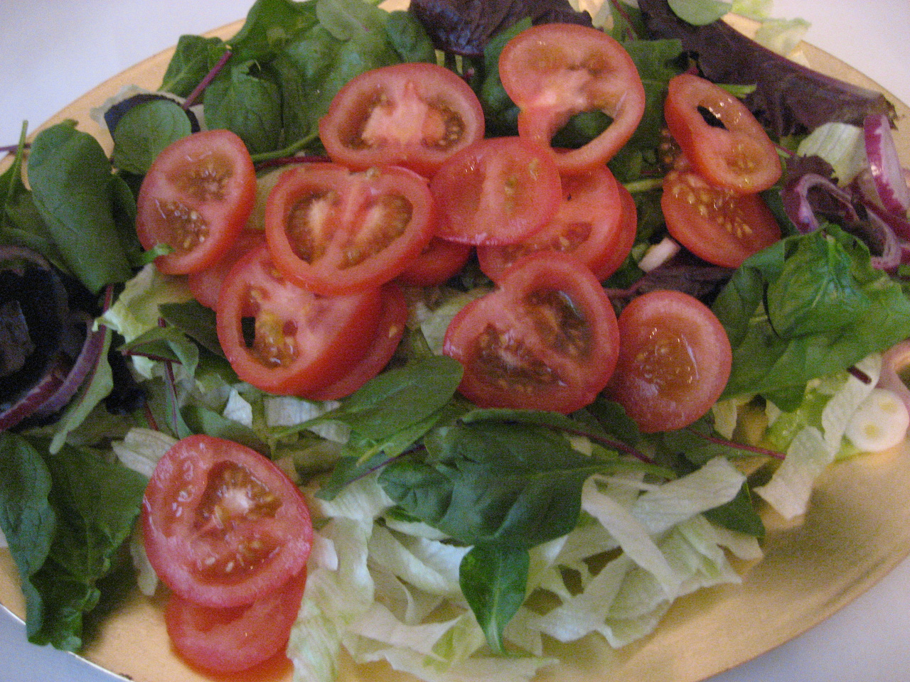 a plate of salad with tomatoes and lettuce