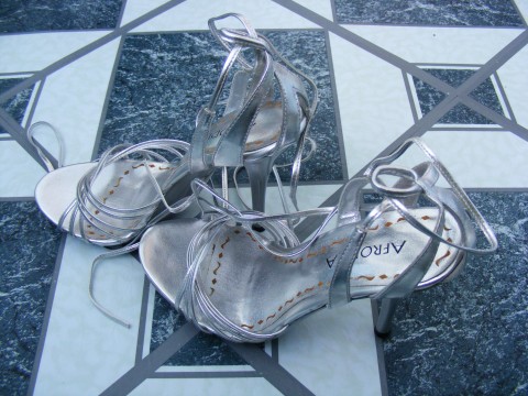 silver sandals with heels are sitting on a tile floor
